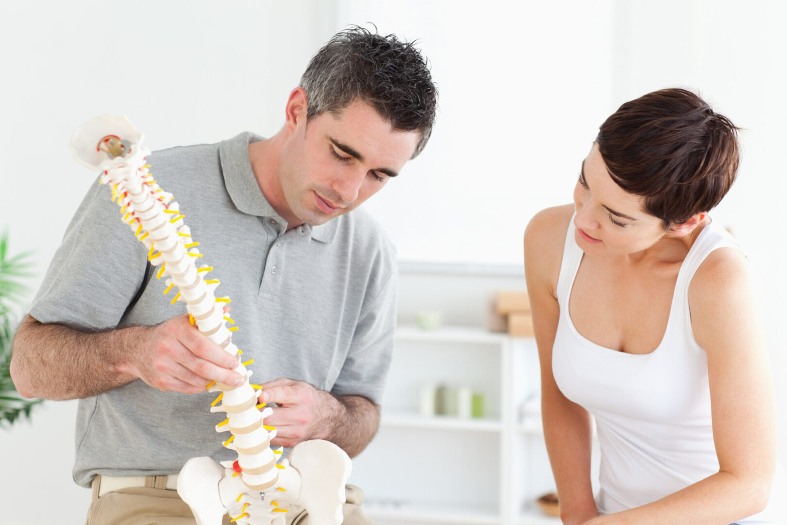 Chiropractor,And,Patient,Looking,At,A,Model,Of,A,Spine